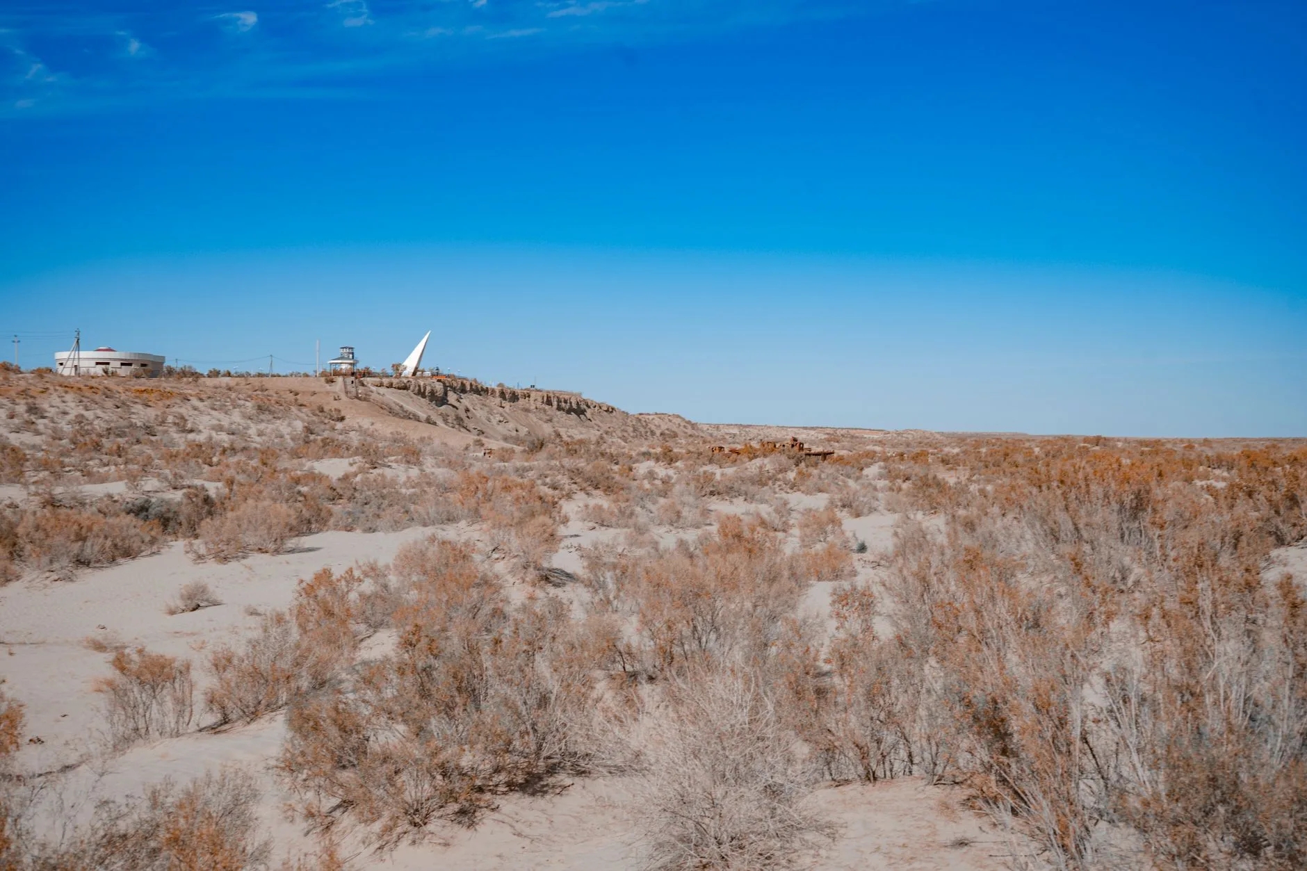 Paysage aride du Karakalpakstan avec structures abandonnées dans le désert d'Ouzbékistan